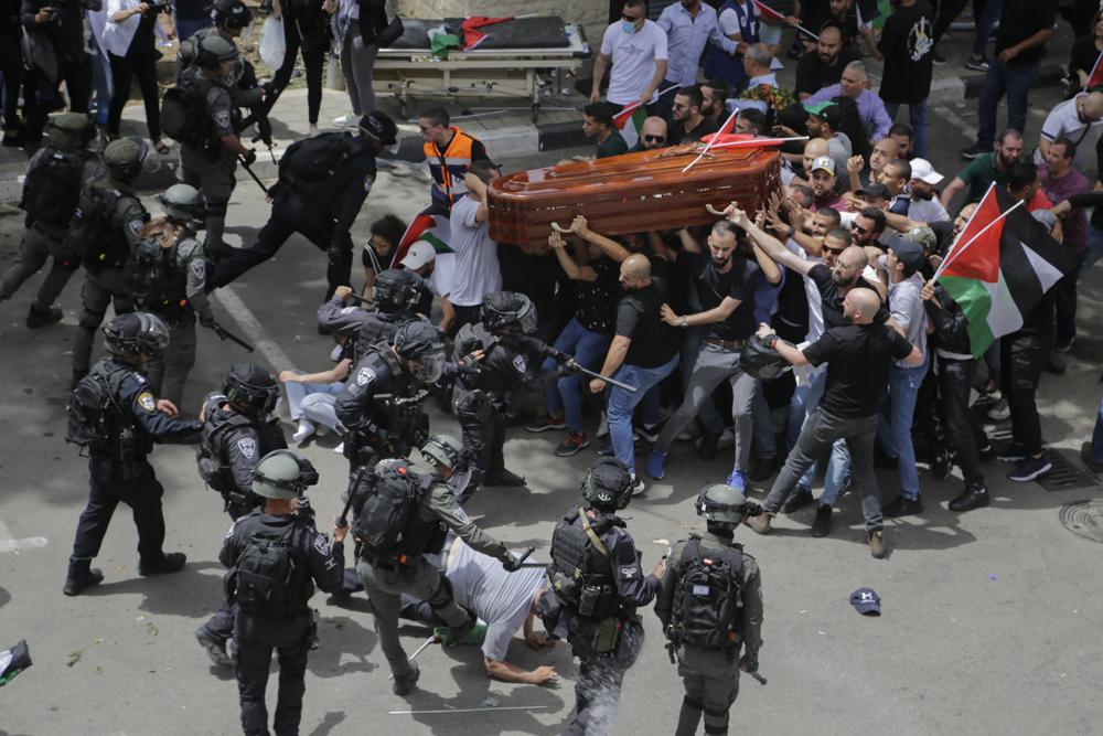 Israeli police confront with mourners as they carry the casket of slain Al Jazeera veteran journalist Shireen Abu Akleh during her funeral in east Jerusalem, Friday, May 13, 2022. Abu Akleh, a Palestinian-American reporter who covered the Mideast conflict for more than 25 years, was shot dead Wednesday during an Israeli military raid in the West Bank town of Jenin. (AP Photo/Maya Levin