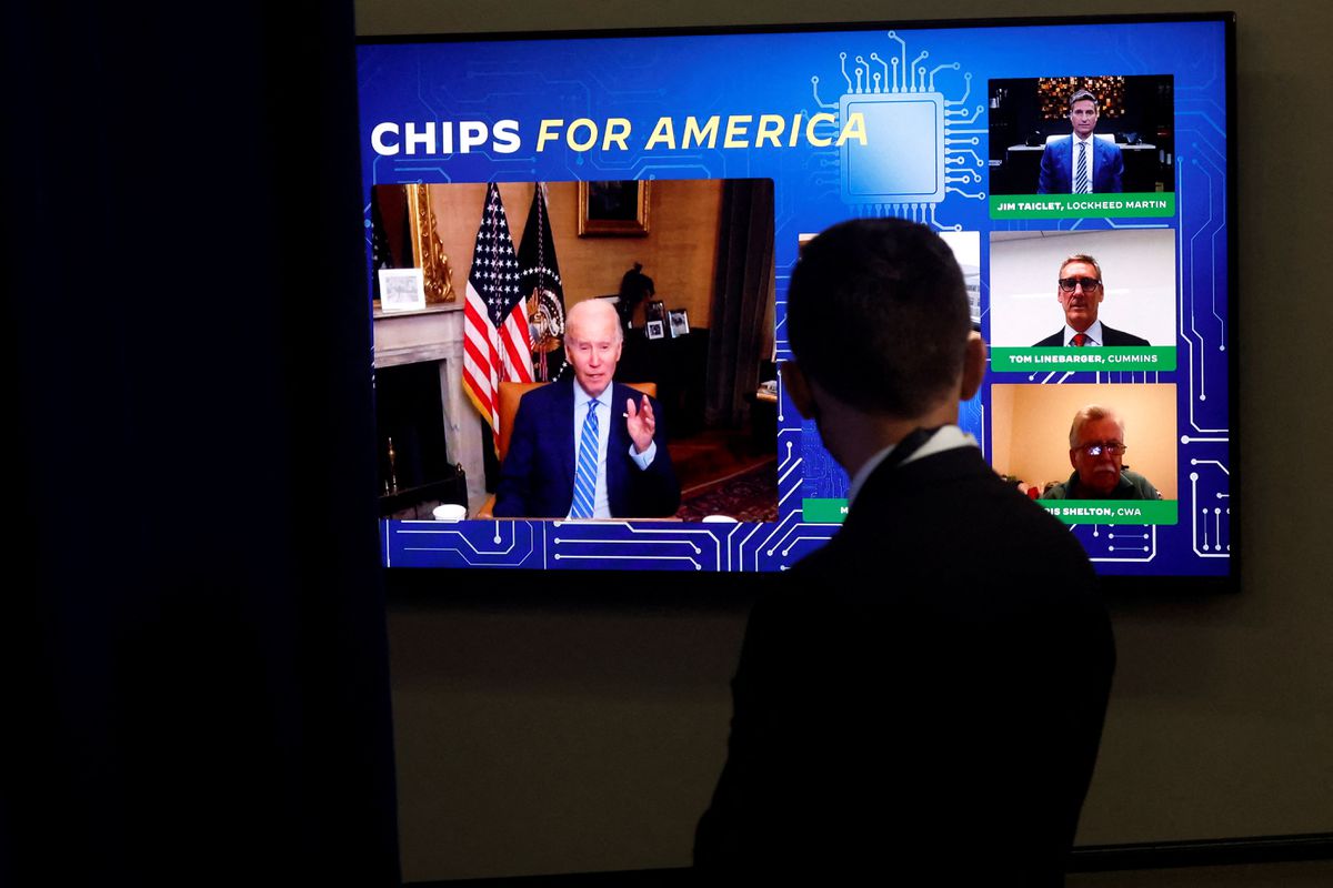 A White House press aide looks on as U.S. President Joe Biden, isolating following his COVID-19 diagnosis, appears virtually in a meeting with business and labor leaders about the Chips Act — relating to U.S. domestic chip and semiconductor manufacturing — in an auditorium on the White House campus in Washington, U.S., July 25, 2022. REUTERS/Jonathan Ernst