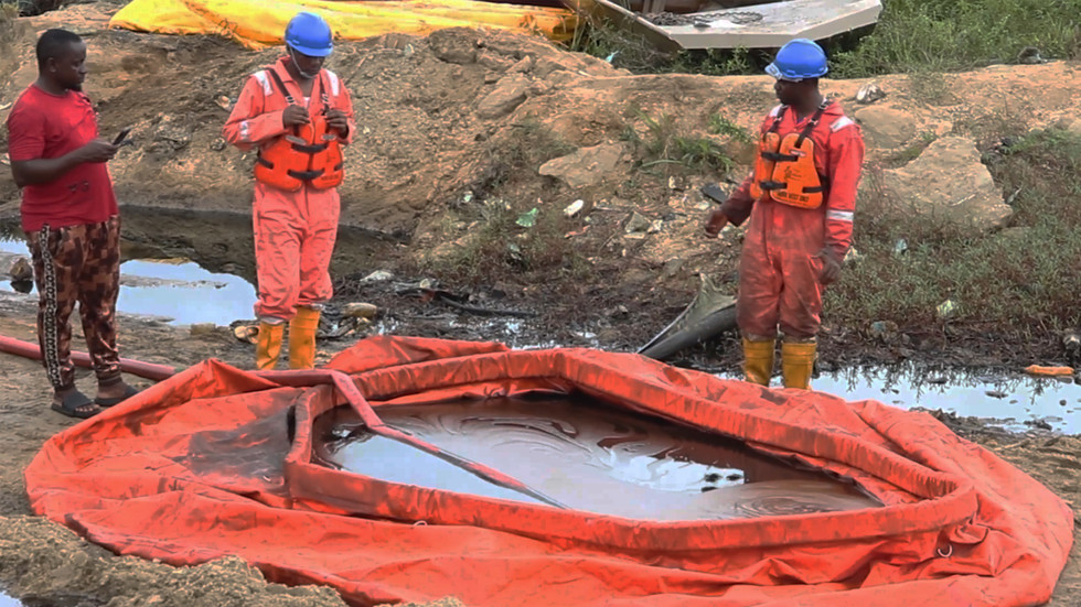 In this grab taken from video, workers stand by a container to collect oil spill waste, in Ogoniland, Nigeria, June 16, 2023. An oil spill at a Shell facility in Nigeria has contaminated farmland and a river. © AP Photo